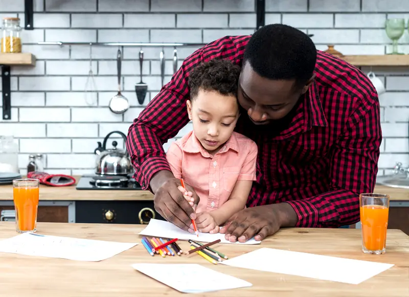 A man and his son are drawing on paper.