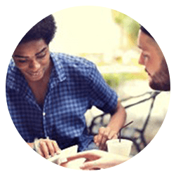 Two people sitting at a table eating food.